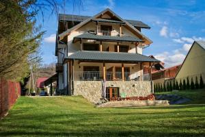 a large house with a green lawn in front of it at Apartamenty Magia Gór in Szczawnica