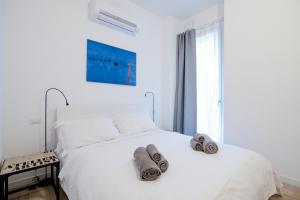 ein weißes Schlafzimmer mit einem Bett mit Handtüchern darauf in der Unterkunft Borgovico Garden - The House Of Travelers in Como