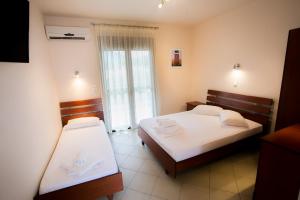a hotel room with two beds and a window at Malamatenia House in Sarti