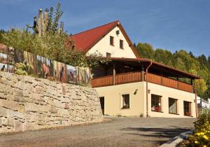 a large white building with a stone wall at Penzion Tuček Adršpach in Adršpach