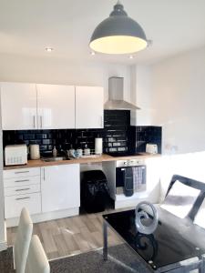 uma cozinha com armários brancos e uma mesa de centro em BELMONT Apartments em Liverpool