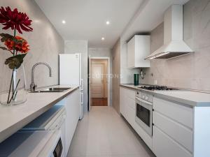 a kitchen with white appliances and a vase with a red flower at Boutique Apartment - 2 Bedroom - Lisbon City Center in Lisbon