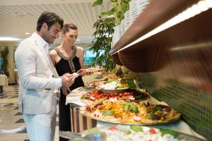 a man and a woman standing in front of a buffet at Aparthotel Holiday in Bibione