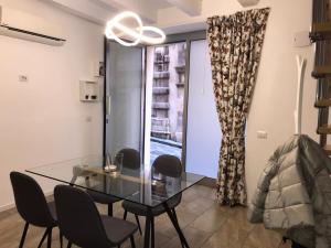 comedor con mesa de cristal, sillas y ventana en A Casa di Vale, en Siracusa