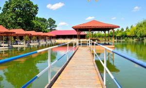 a dock with a pavilion on the water in a lake at Hotel Popasul Iancului in Corbii Mari