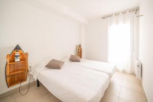 a white bedroom with a bed and a window at Apartment Meritxell in L'Escala