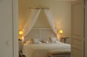 a bedroom with a white bed with a canopy at Mas De Chastelas in Saint-Tropez
