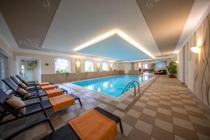 a large swimming pool with chairs and a table at Aktiv & Wellnesshotel Zentral in Prato allo Stelvio