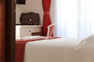 a bedroom with a bed and a suitcase in a window at Hotel Du Soleil in Rimini