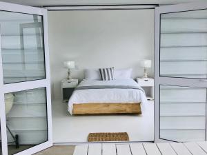 ein weißes Schlafzimmer mit einem Bett und einem Spiegel in der Unterkunft Seascape in De Kelders