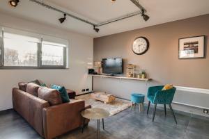 a living room with a couch and a clock on the wall at K & N Appartement à 1 km du circuit in Francorchamps