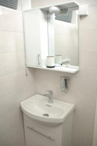 a white bathroom with a sink and a mirror at Apartmani Seyda in Sarajevo
