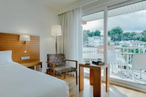 um quarto com uma cama, uma cadeira e uma janela em Hesperia Ciudad de Mallorca em Palma de Maiorca
