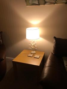 a lamp sitting on a table next to a couch at Ponderosa Cottage Lisburn Free Gated Parking M1 & City all close by in Lisburn