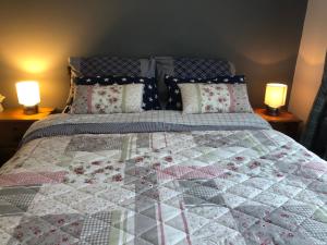 Una cama con edredón y dos lámparas. en PondeROSEa Cottage Free Gated Parking M1 & City location, wood stove, en Lisburn