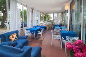 un restaurante con mesas y sillas azules y ventanas en Hotel Cheri, en Rímini