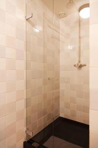 a white tiled bathroom with a glass shower door at Logement Swaenenvecht in Utrecht