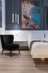 a bedroom with a bed and a black chair at Sicily 4 Suite in Catania