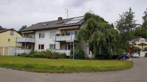 ein weißes Haus mit einem Baum davor in der Unterkunft Haus Weyers in Kressbronn am Bodensee