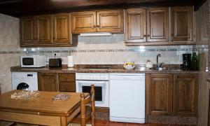 a kitchen with wooden cabinets and a white dishwasher at La Ermita in Loroñe