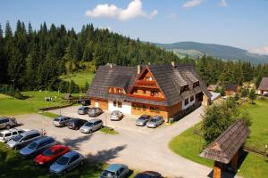 a large house with cars parked in a parking lot at Wellness Penzion u Michala in Zuberec
