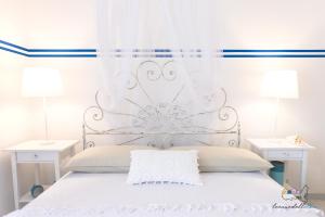 un letto bianco con testata metallica e due lampade; di Casa Tellina a Marina di Campo