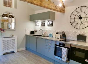 a kitchen with blue cabinets and a large clock on the wall at The Stables in Monmouth