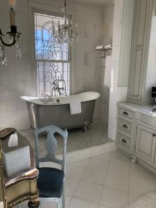 uma casa de banho com uma banheira, uma cadeira e uma janela em The Twelve Oaks Bed & Breakfast em Covington