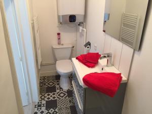 a bathroom with a toilet and a sink with red towels at Les Clochers d'Or in Chartres