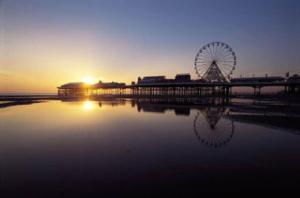 a ferris wheel on a pier with the sunset in the background at The Regal Hotel in Blackpool