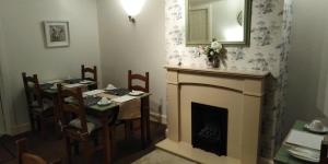 a dining room with a fireplace and a table and chairs at 29 Well Street B&B in Moffat
