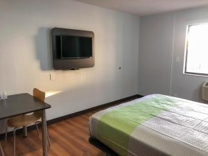 a bedroom with a bed and a table and a tv on the wall at Studio 6 Wichita, KS - Airport in Wichita