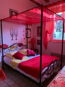 a bedroom with a four poster bed with red sheets at Les Studios de Soizick in Amboise