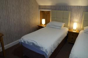 
a hotel room with two beds and two lamps at Myrtle Bank Hotel in Gairloch
