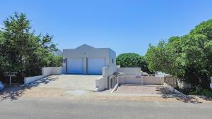 a large white house with a blue garage at Angel's Place by the Sea in Hermanus