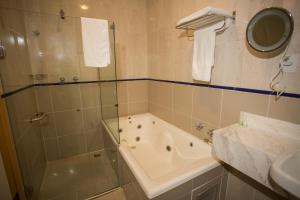 a bathroom with a shower and a tub and a sink at Pousada Solar da Ópera in Ouro Preto