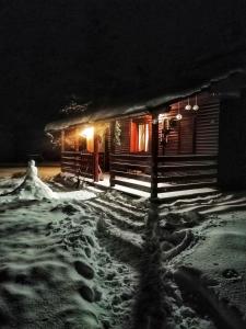 a cabin in the snow at night with lights at Woodpeckers house in Zlatibor
