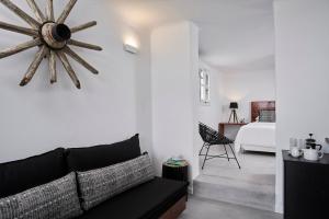 a living room with a black couch and a bedroom at Almyra Guest Houses in Paraga