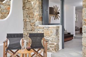 two chairs in a living room with a stone wall at Almyra Guest Houses in Paraga