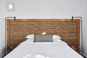 a bedroom with a large white bed with a wooden headboard at Almyra Guest Houses in Paraga