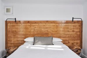 a bed with a wooden headboard with a pillow on it at Almyra Guest Houses in Paraga