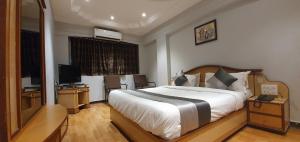 a bedroom with a large bed and a television at Hotel JMC Group in Rajkot