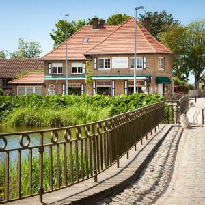 a bridge over a river with a building in the background at Logies Noorderlicht in Damme