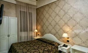 ヴィテルボにあるパラッツォ リアリオのベッド1台、テーブル2台、ランプ2つが備わるホテルルームです。