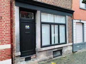 una puerta negra en el lateral de un edificio de ladrillo en Roture 88 en Lieja