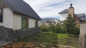 ein Haus mit einer Steinmauer neben einem Gebäude in der Unterkunft Cabaña en Caviahue in Caviahue