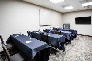 a conference room with black tables and chairs and a screen at Wingate by Wyndham Denver Airport in Denver