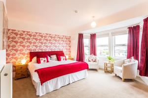 a bedroom with a red and white bed and windows at Aquila Heights Guest House in Dorchester