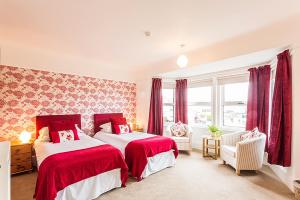 a bedroom with two beds with red and white sheets at Aquila Heights Guest House in Dorchester