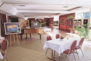 a room with tables and chairs and a painting on the wall at Hotel M Jacobs GmbH in Gummersbach